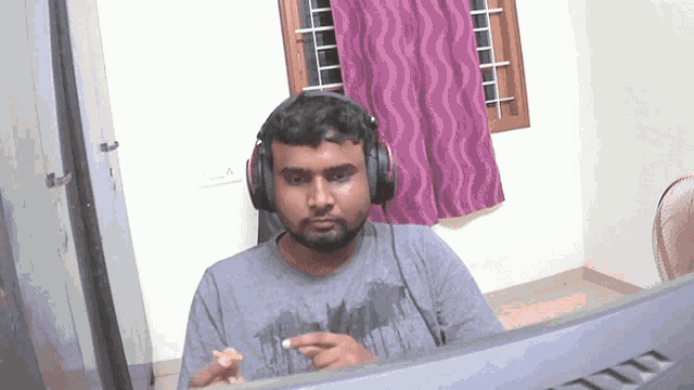 a man wearing headphones and a batman shirt looks at a computer screen