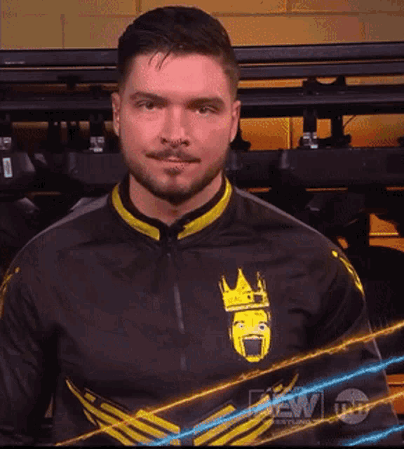 a man with his arms crossed is wearing a black and yellow jacket with a crown on it