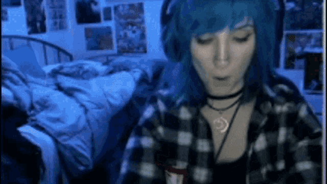 a woman with blue hair is wearing headphones and a plaid shirt .