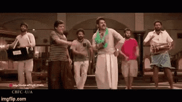 a group of men are dancing in a room while one man is holding a drum .