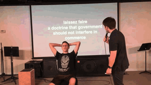 a man sits in front of a screen that says " laissez faire "