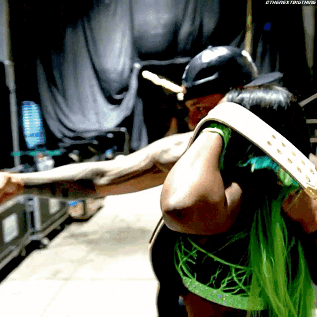 a woman in a green top is hugging a man in a baseball cap