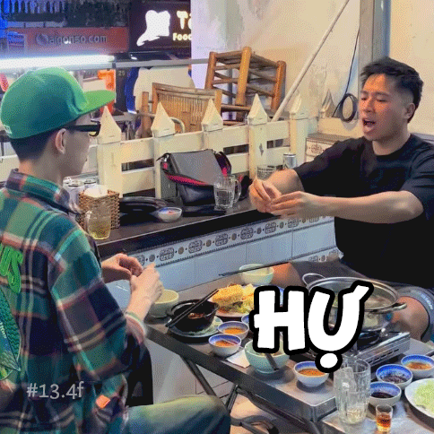 two men sitting at a table with a sign that says hu on it