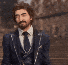 a man in a suit and tie is pointing at something in the distance .