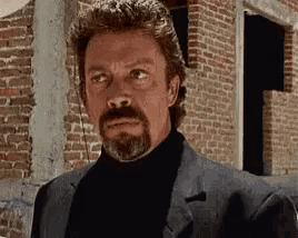 a man with a beard is wearing a suit and a black turtleneck .