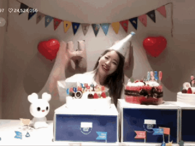 a woman wearing a party hat stands in front of a cake