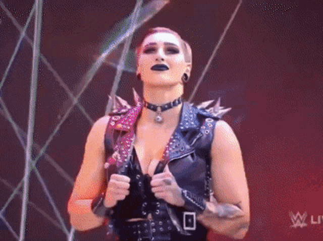 a woman in a leather vest is standing on a stage .