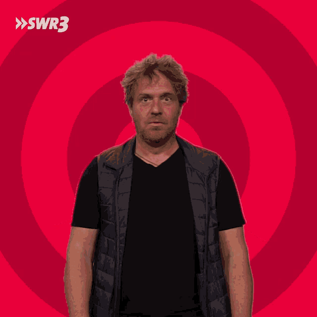a man with a surprised look on his face is standing in front of a red background with swr3 on it