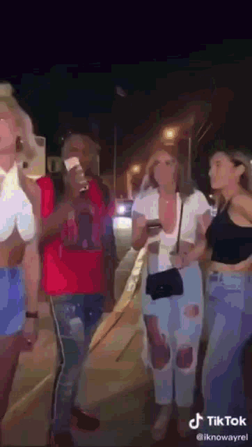 a group of people are standing on a sidewalk at night .