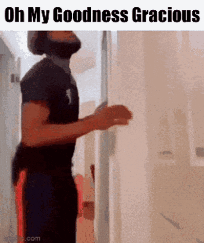 a man with a beard is standing in front of a door with the words oh my goodness gracious above him .