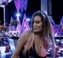 a woman in a black bikini top is standing in front of a mirror .