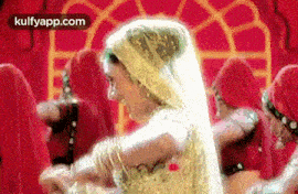 a woman in a white dress is dancing in front of a group of women in red dresses .