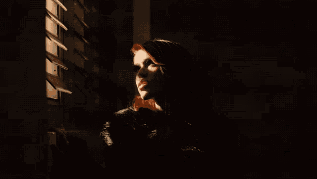 a woman in a fur coat is standing in the dark