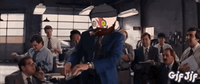 a man with a beard is standing in front of a group of men in suits and ties with gif jif in the corner