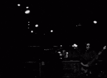 a blurry black and white photo of a man playing a guitar .