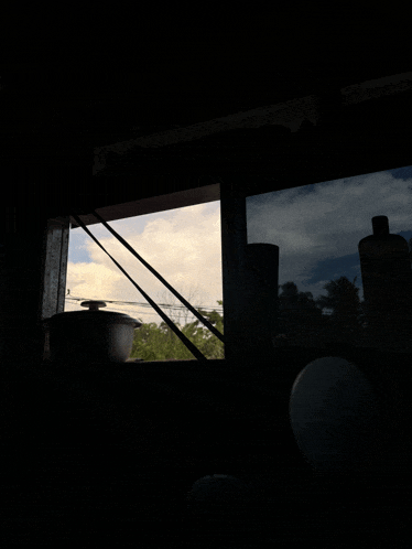 a window with a view of a cloudy sky and trees