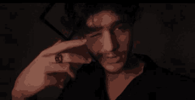 a man with a ring on his finger is making a funny face in the dark .