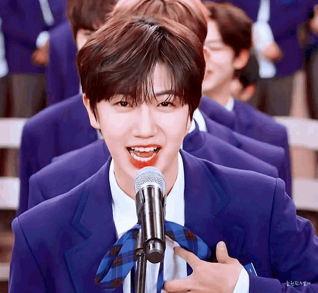 a boy in a blue suit is singing into a microphone