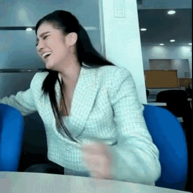 a woman in a green jacket is laughing while sitting at a table
