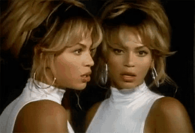 a woman in a white top is looking at herself in a mirror .