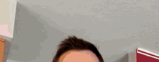 a close up of a man 's head with a gray wall in the background