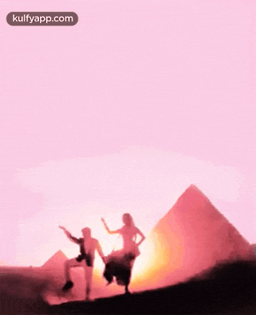 a man and a woman are dancing in front of the pyramids .
