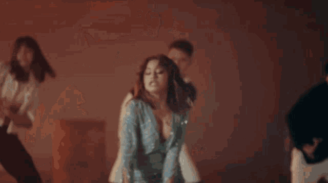 a woman in a blue dress is dancing in a room with other people .
