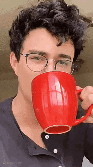a young man wearing glasses is drinking from a red cup