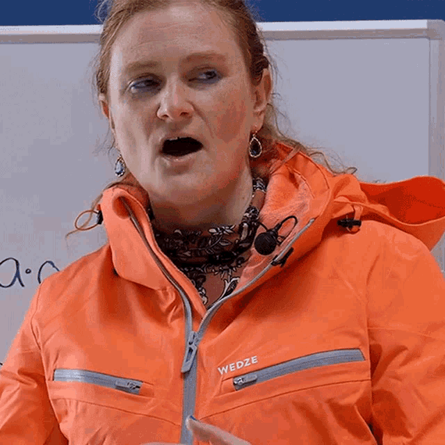 a woman wearing an orange jacket with the word wedze on the front