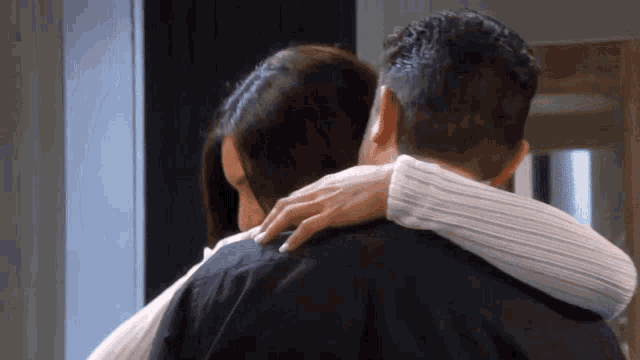 a man and a woman are hugging each other in a room .