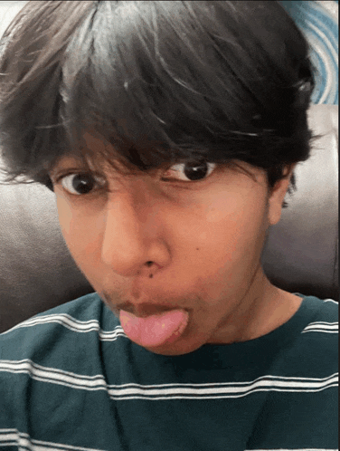 a person sticking their tongue out and wearing a green and white striped shirt