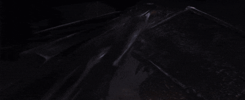 a person is standing in the dark in a dark room with smoke coming out of their mouth .