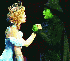 a woman in a blue dress is holding hands with a green woman