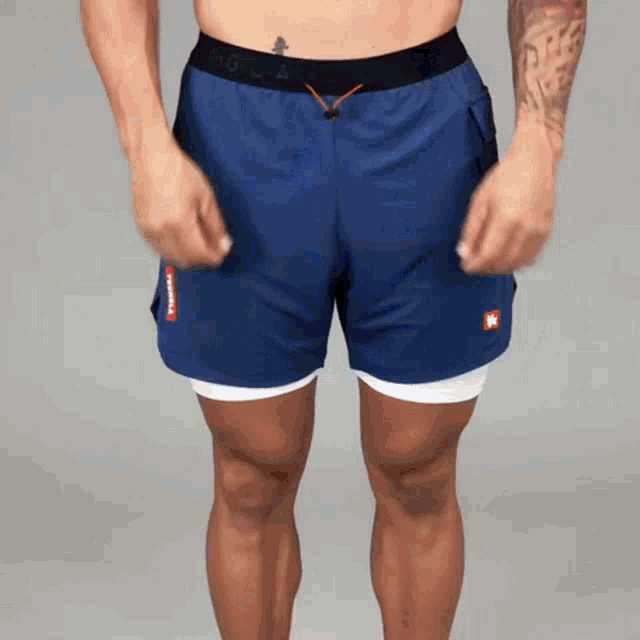 a man without a shirt is wearing a pair of blue shorts with a red k on them