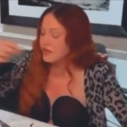 a woman with red hair is sitting at a table with her eyes closed and a leopard print shirt on .
