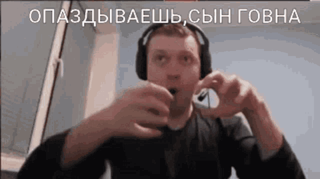a man wearing headphones is making a heart shape with his hands while holding something in his mouth .