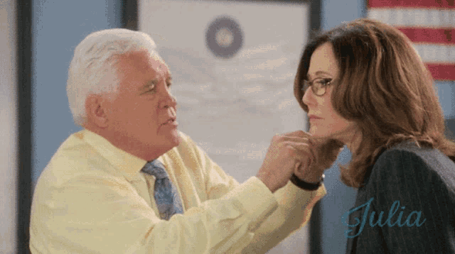 a man in a yellow shirt and tie touches a woman 's face with the name julia written on the bottom