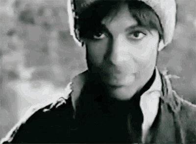 a black and white photo of prince wearing a beanie and a jacket .