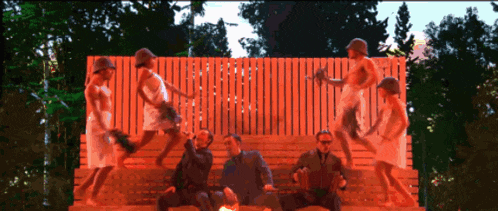 a group of people are standing and sitting on a bench