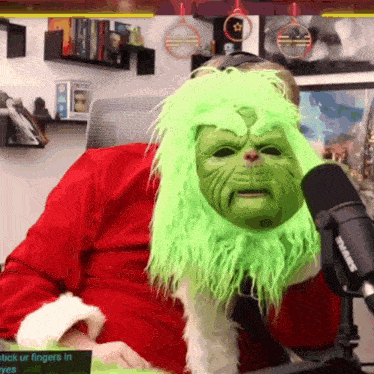 a man is wearing a green grinch mask and a shure microphone
