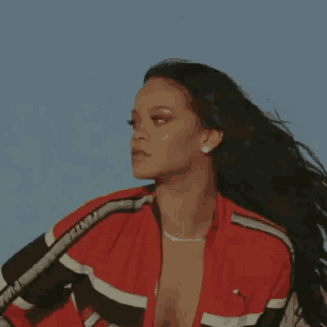 a woman with long hair is wearing a red and black jacket and a plunging neckline .