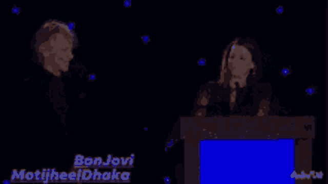 a man and a woman are standing in front of a podium with the name bonjovi motijheel dhaka on it