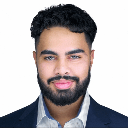 a man with a beard wears a blue jacket and white shirt