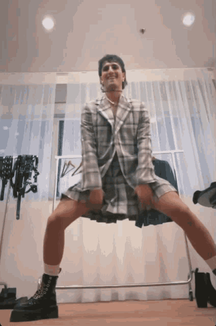 a man wearing a plaid jacket and skirt is dancing