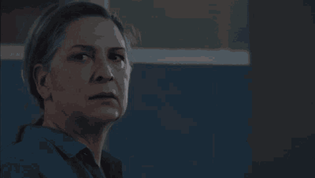 a close up of a woman 's face with gray hair and a blue shirt .