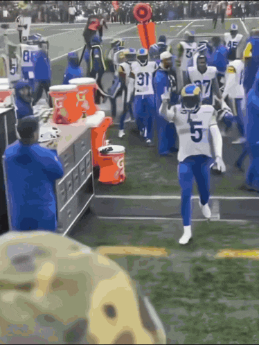 a football player wearing a number 5 jersey is running on the field