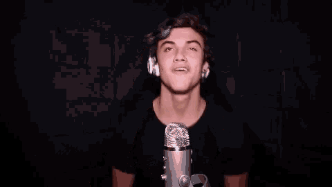 a young man wearing headphones is standing in front of a microphone and saying grandm .