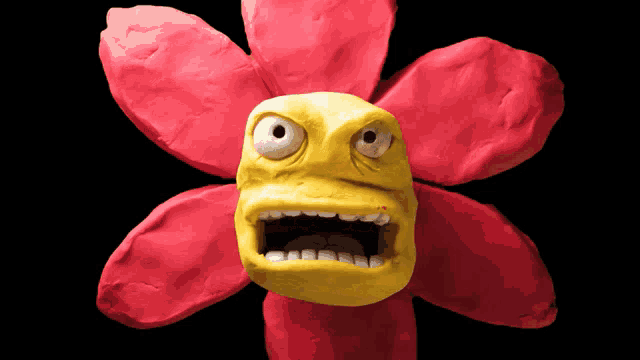 a clay flower with a yellow face and a black background