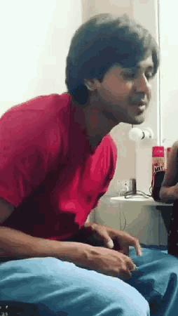 a man in a red shirt is sitting in front of a fan