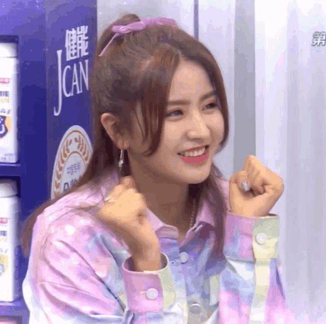 a girl with a ponytail is smiling in front of a sign that says j can
